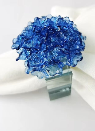 Decorative table setting with a blue acrylic blossom napkin ring on toile de jouy patterned napkin