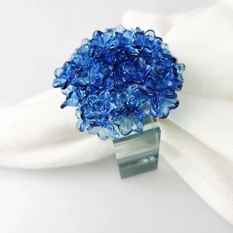 Decorative table setting with a blue acrylic blossom napkin ring on toile de jouy patterned napkin