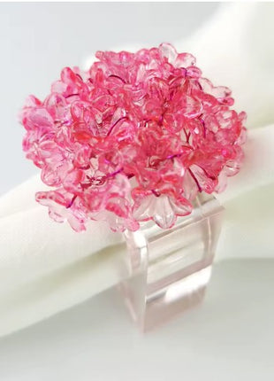 Decorative table setting with a pink acrylic blossom napkin ring on toile de jouy patterned napkin