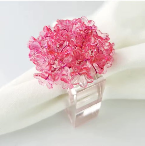 Decorative table setting with a pink acrylic blossom napkin ring on toile de jouy patterned napkin