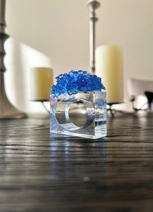 Decorative table setting with a blue acrylic blossom napkin ring on toile de jouy patterned napkin