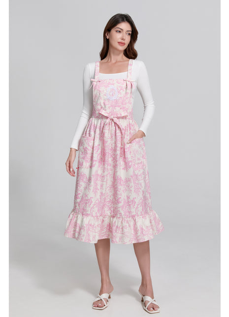 Model wearing a pink toile de jouy floral apron with a gray background