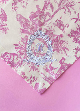 Pink toile de jouy floral patterned napkins with royal emblem embroidery