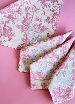 Pink toile de jouy floral patterned napkins with royal emblem embroidery