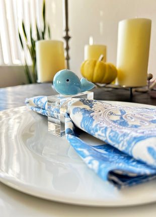 Decorative table setting with a blue whale napkin ring on toile de jouy patterned napkin