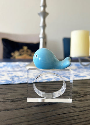 Decorative table setting with a blue ceramic whale napkin ring on toile de jouy patterned napkin