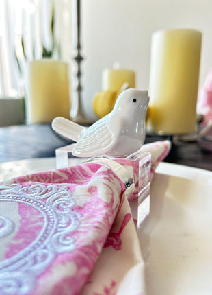 Decorative table setting with a white finch napkin ring on toile de jouy patterned napkin