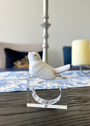 Decorative table setting with a white ceramic finch napkin ring on toile de jouy patterned napkin