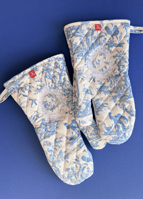 Pair of blue toile de jouy patterned oven mitts with royal emblem embroidery