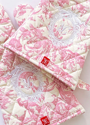 Pair of pink toile de jouy patterned ovenmitts with royal emblem embroidery 