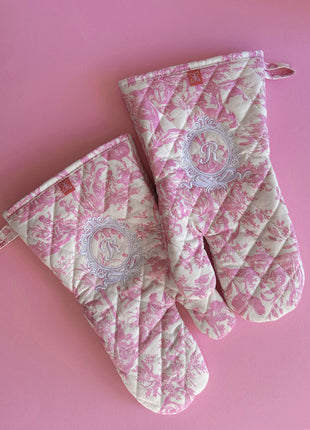 Pair of pink toile de jouy patterned ovenmitts with royal emblem embroidery 
