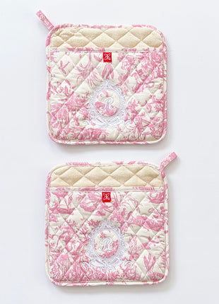 Pair of pink toile de jouy patterned pot holders with royal emblem embroidery 