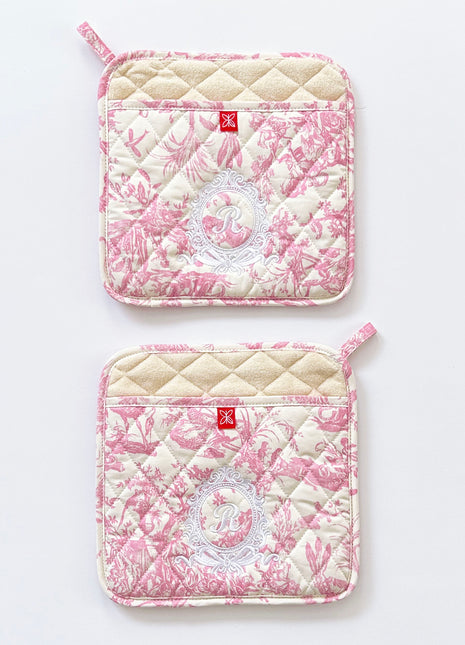 Pair of pink toile de jouy patterned pot holders with royal emblem embroidery 