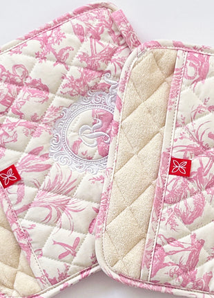 Pair of pink toile de jouy patterned pot holders with royal emblem embroidery 
