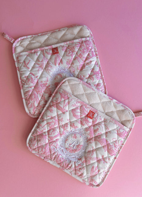 Pair of pink toile de jouy patterned pot holders with royal emblem embroidery